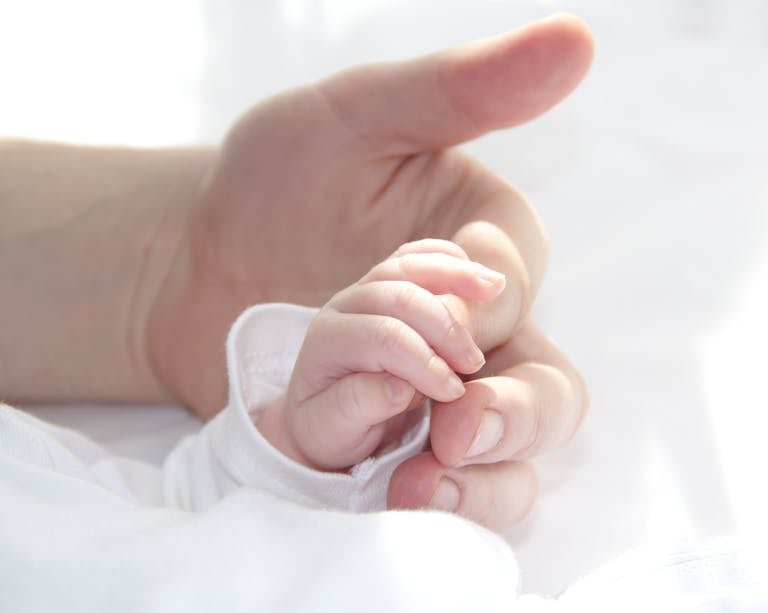 Close-up of a baby's hand holding Daddy's finger, symbolizing love and connection.