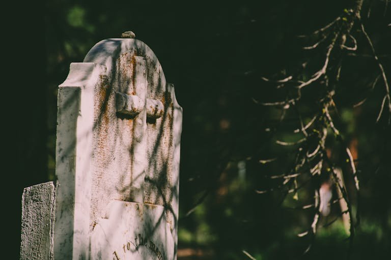 Close-up of a weathered tombstone with a cross